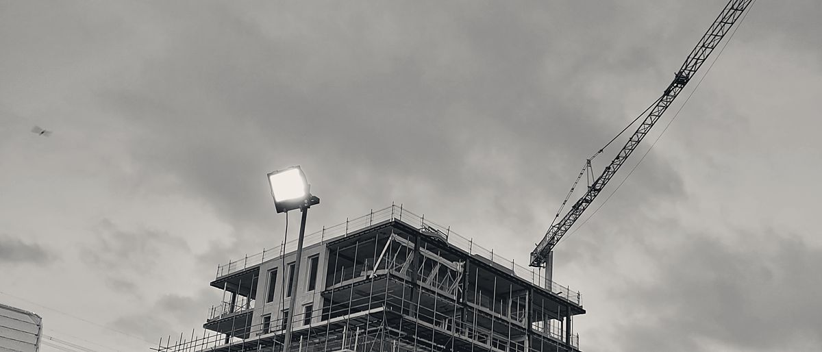 De campus van Husky in aanbouw bij schemer, met torenkraan boven de ruwbouw