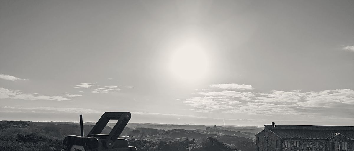 Werken op het dak aan de Katwijkse kust, met de duinen en het monumentale pand op de achtergrond