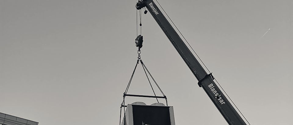 Een koelmachine hangt aan de kraan boven de stad
