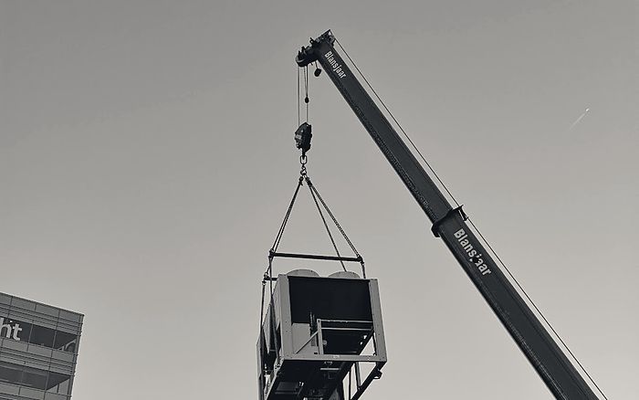 Een koelmachine hangt aan de kraan boven de stad