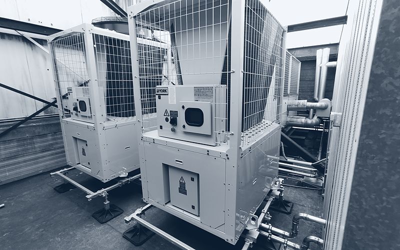 Twee koelmachines opgesteld op een dak, aangesloten op het leidingwerk